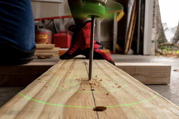 BullseyeBore Core on a drill creating precise holes in wood, with laser guide visible