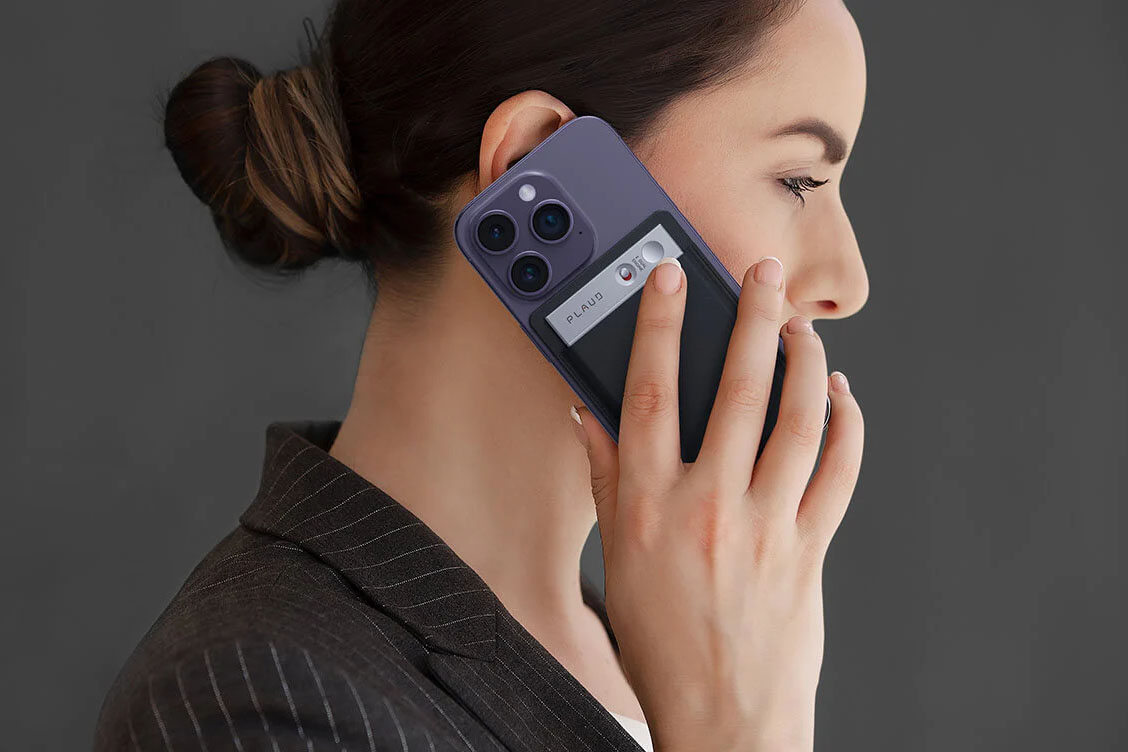 Woman holding an iPhone to her ear with Plaud Note attached.