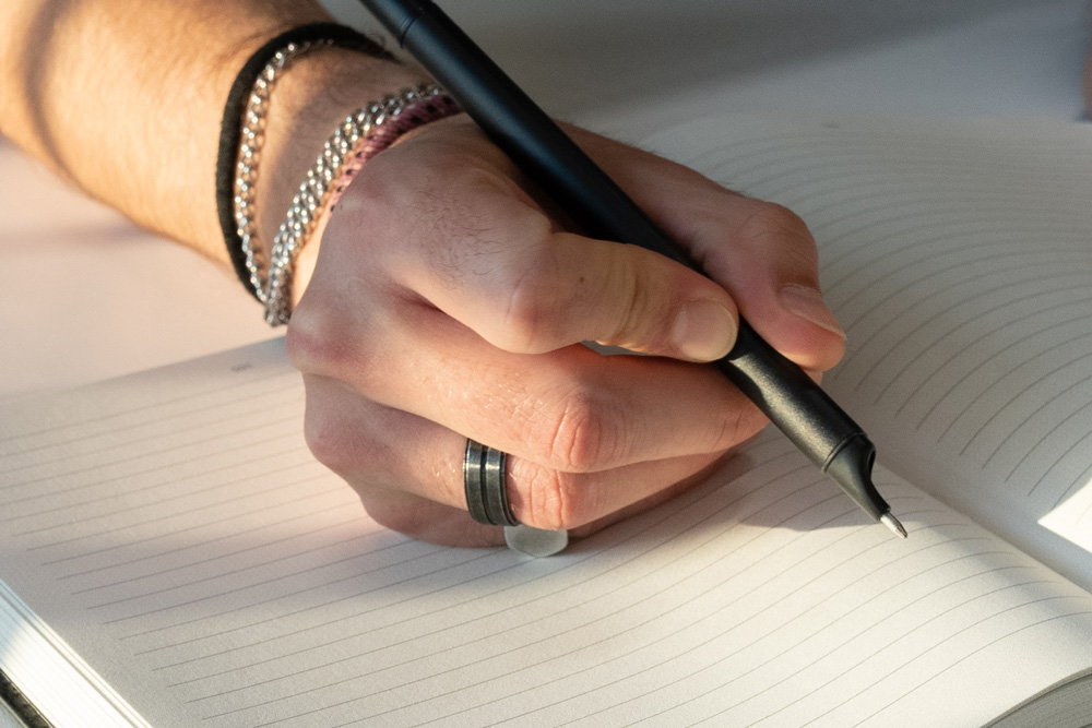 Close-up of hand writing in a notebook with a XNote