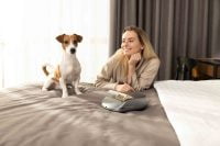 Dog sitting next to Creatulize X1 on a bed