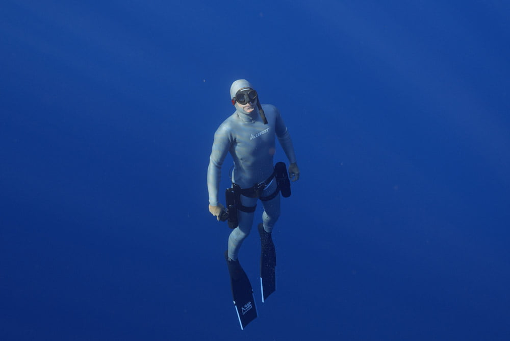 Diver in a wetsuit ascending in blue water with the LEFEET P1 scooter