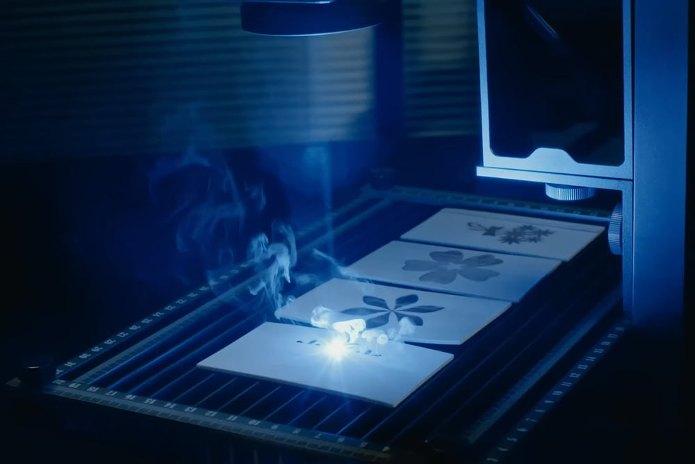 Longer Nano engraving intricate designs on paper under blue light