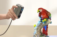 Hand holding Seal 3D scanner scanning a parrot sculpture