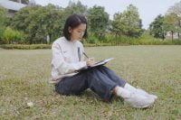 Woman outdoors, writing in a smart notebook with SyncPen 4