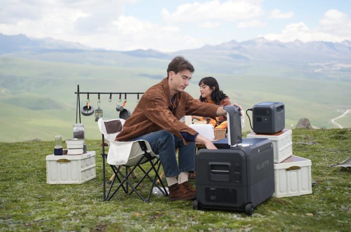 Couple with BLUETTI SwapSolar station at a mountain picnic