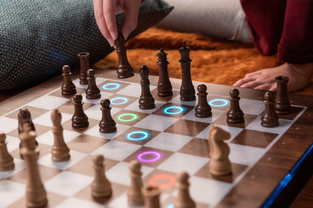 Hand selecting a chess piece with illuminated possible moves on board