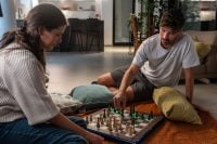 Two people playing chess with GoChess indicating moves.