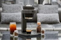 KUKU Maker on a glass table with coffee and coffee beans around it.