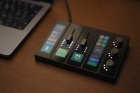 Modue device with sliders and dials beside a laptop