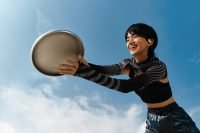 Woman smiling while catching a disc, wearing OWS Sports earphones