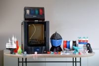 Wider shot of Phrozen Arco 3D printer with various printed objects and filament spools