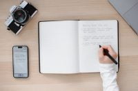 Top view of a desk with a notebook, smartphone, and XNote