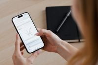 Smartphone displaying a drawn graph beside a notebook
