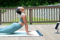 Practitioner on YogiFi Smart Mat with a tablet showing yoga