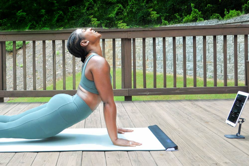 Practitioner on YogiFi Smart Mat with a tablet showing yoga