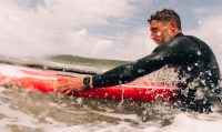 Man surfing with Apple Watch Series 10, wearing a wetsuit in the ocean with waves splashing.