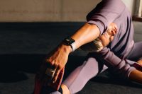 Woman stretching in a gym, wearing Apple Watch Series 10 with a white band, focused on workout tracking.