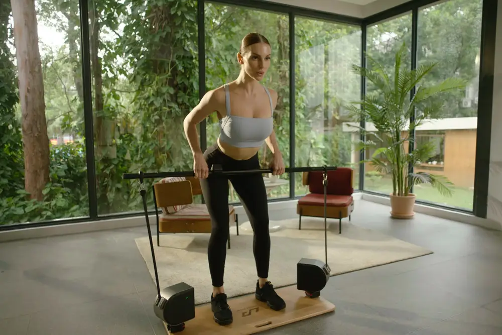 Woman exercising with Unitree PUMP MAX in a home gym, focusing on pulling movements with bar attachment.